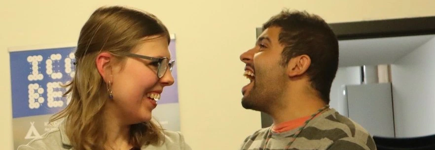 To people standing close to each other having a conversation. Both are laughing joyfully.